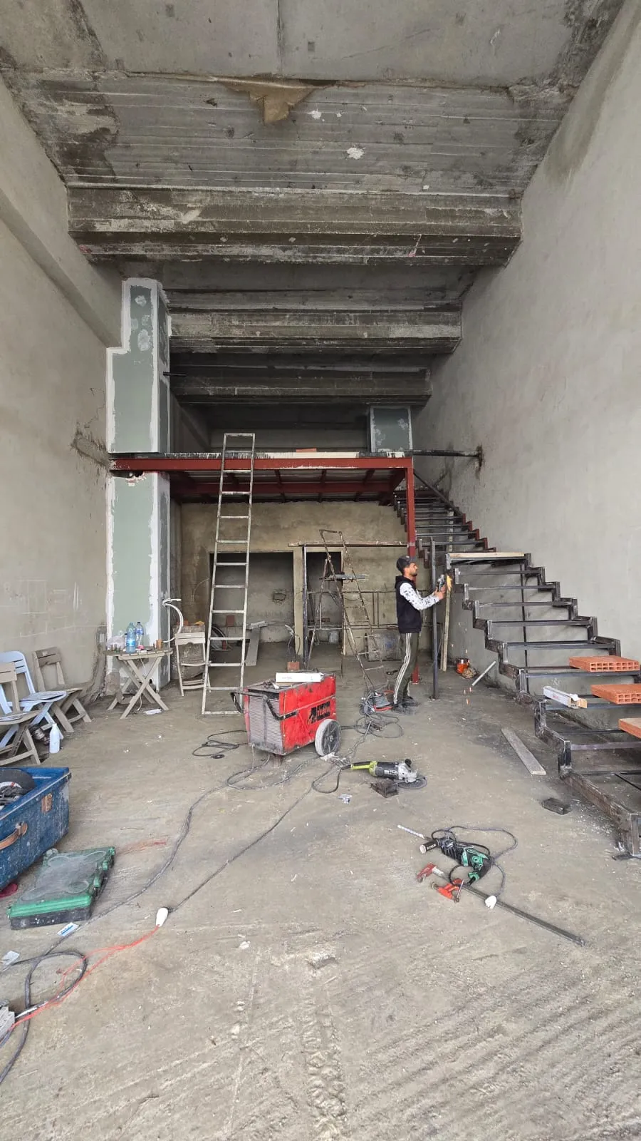 Local commercial à l'état brut, escalier métallique en cours de fabrication
